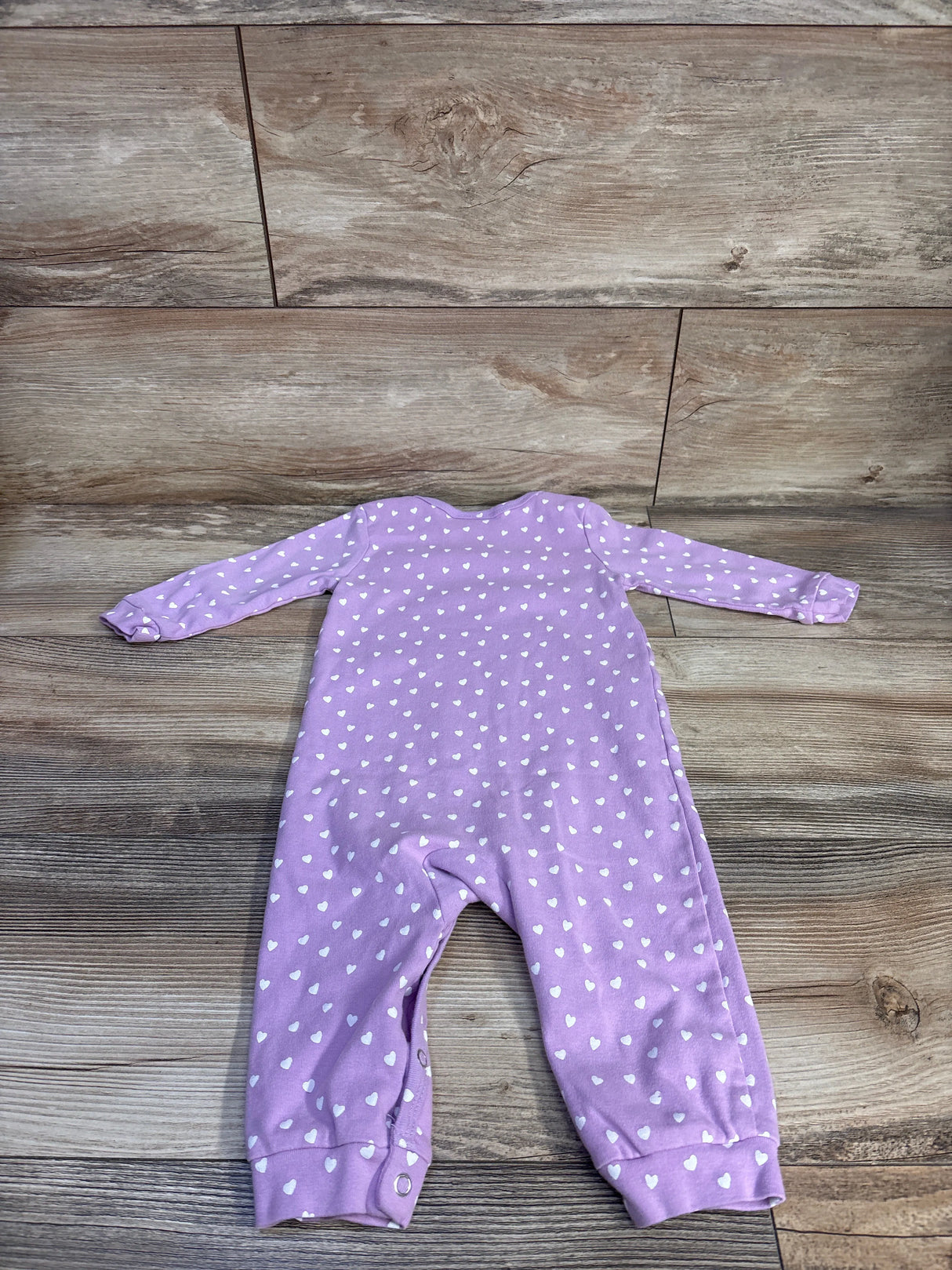 Flat-lay of purple PatPat Care Bears heart print long-sleeve coverall showcasing white hearts all over and snap cuffs on a wood floor