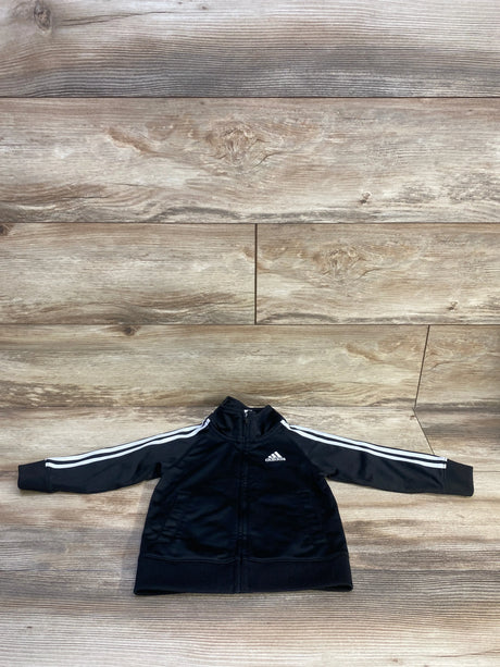 Front view of black Adidas toddler full-zip track jacket showing white three stripes on sleeves, chest logo, zip pockets on wood background