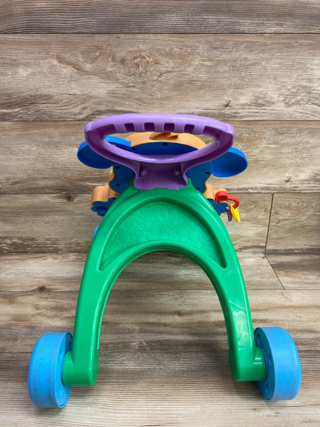 Rear view of Fisher Price Learn With Puppy Walker showing purple handle and blue wheels on wood-look floor