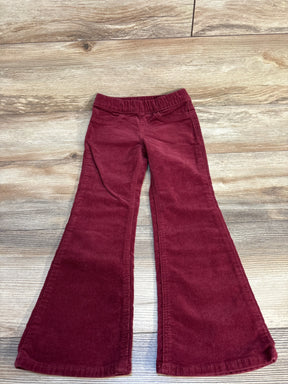 Red corduroy kids bell bottom pants with elastic waistband on wood background