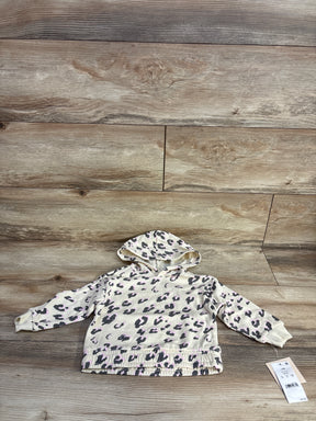 Cream-colored toddler hoodie with black and pink leopard print on wood background