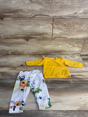 Baby outfit with yellow long sleeve top and white floral printed pants on wood floor