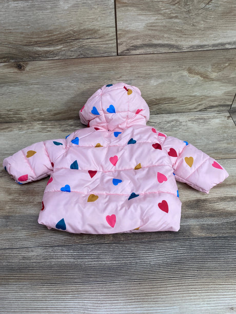 Back view of pink hooded puffer jacket showcasing a colorful heart pattern and quilted design on a wood floor