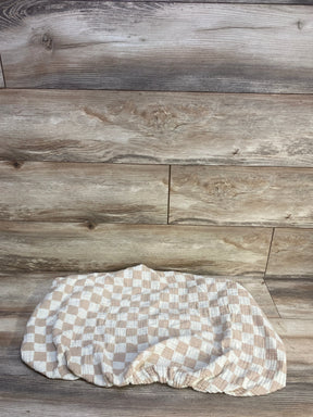 Flat lay of Brixton Phoenix muslin bassinet sheet showcasing checker pattern and elastic fitted edge on wood background
