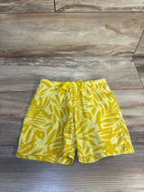 Yellow toddler shorts with leaf print pattern and drawstring waistband on wood background