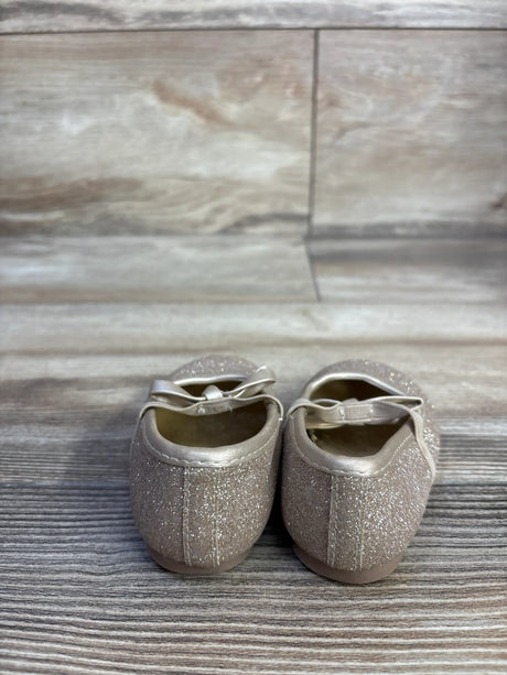 Rear view of Koala Kids gold glitter bow ballet flats showcasing glitter finish and elastic bow strap on wood-plank background