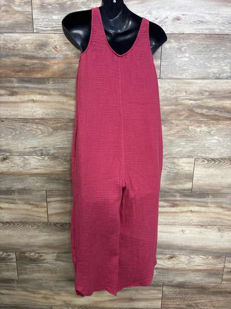 Front view of burgundy maternity gauze jumpsuit with V-neck and wide legs on a black mannequin against wood background