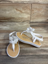 Front-angle of Bebe chiffon flower sandal showcasing sheer white chiffon flower with rhinestone center on wood background