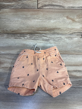 Top-down view of orange toddler twill shorts showcasing elastic drawstring waistband, navy palm tree print, and rolled cuffs on wood floor