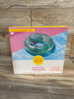 Front view of boxed Sun Squad swim tube with handles showing tropical leaf pattern and 3 ft 5 in diameter label on wood floor