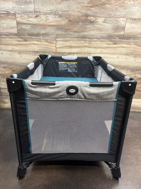 Front view of Graco Pack ‘n Play Portable Playard in Darcie showcasing mesh sides and open play space with wood-look floor background