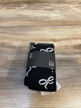 Black Baby Gap tights for toddler girl, age 4-5 years, with white bow pattern, new with tags on wood floor