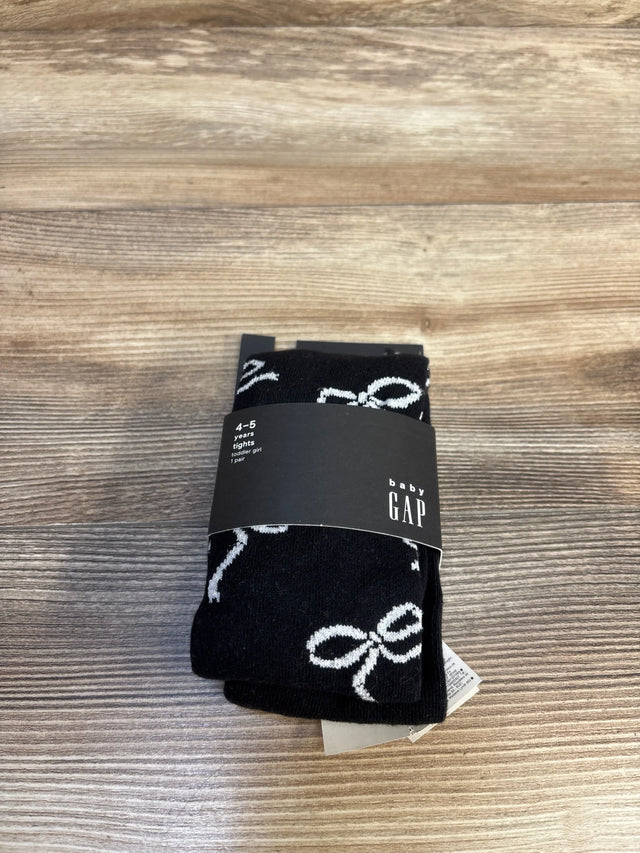 Black Baby Gap tights for toddler girl, age 4-5 years, with white bow pattern, new with tags on wood floor