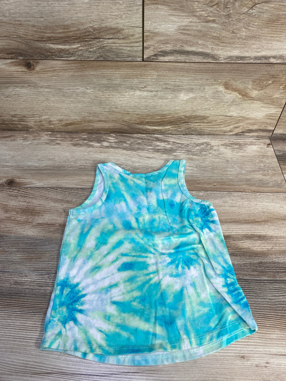 Flat-lay of Cat & Jack toddler tank top showing blue-green tie-dye pattern and A-line shape on wood floor