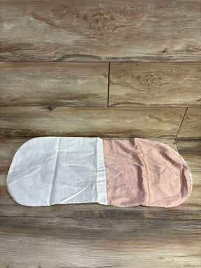 Flat lay of Silky Tots Silk oval bassinet sheet in pink showing two-tone white and light pink panels on wooden floor
