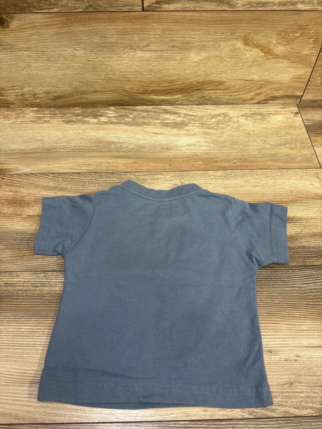 Back view of Talladega Nights Ricky Bobby shirt showcasing its plain blue back and short sleeves on a wood-grain floor