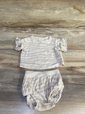 Top-down view of ivory newborn ribbed two-piece: short-sleeve ruffle shirt and bloomers showing ribbed texture on wood background