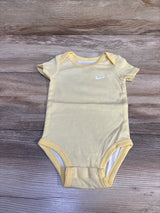Front view of a yellow striped Nike bodysuit showcasing short sleeves and white swoosh logo on a wood-grain background