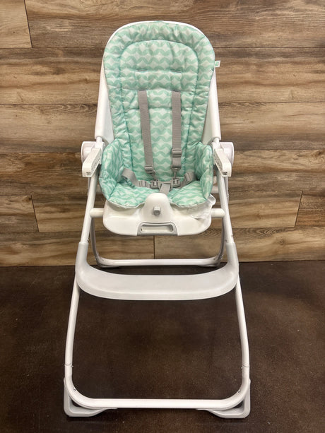 Front view of Ity by Ingenuity Yummity Yum Easy Folding High Chair, Goji, with green patterned seat, harness, and tray