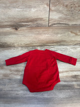 Red long-sleeve baby bodysuit laid flat on wood background, children's clothing resale