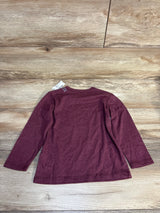 Burgundy long sleeve kids shirt laid flat on wood floor, resale clothing for children