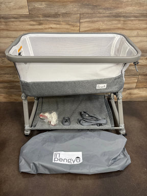 Gray mesh baby bassinet with accessories and 'li'l pengyu' storage bag on wooden floor