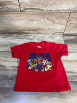 Front view of red Paw Patrol graphic toddler t-shirt size 2T showing five characters and PAW PATROL text on a light wood background
