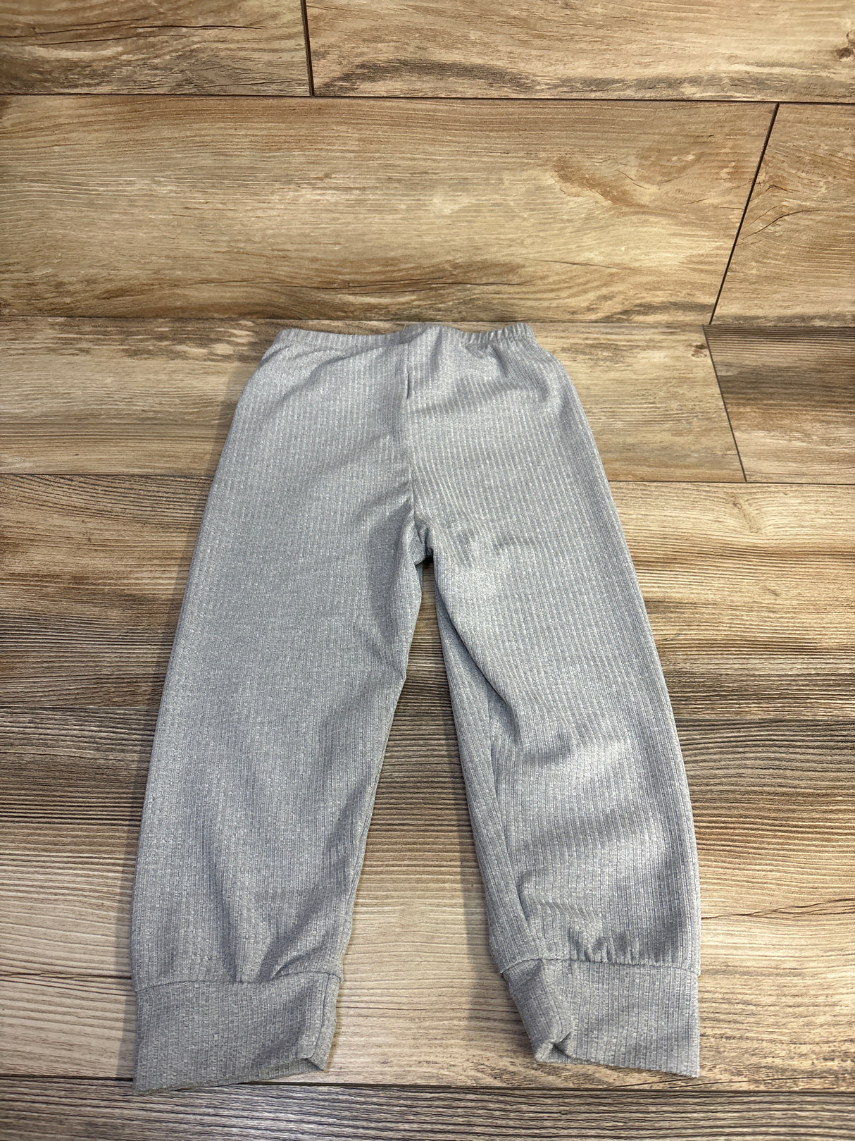 Flat lay of ribbed grey toddler pants size 2-3T showing elastic waistband and cuffed ankles on wood floor