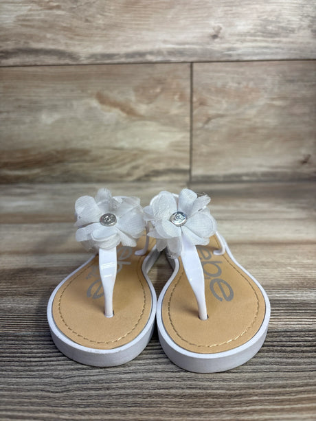 Front view of Bebe white chiffon flower sandals showing fabric flowers with rhinestone centers on wood background