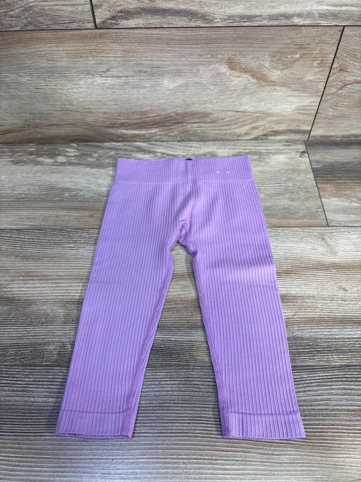 Flat lay of lilac toddler ribbed leggings size 12-24 months with elastic waistband and ribbed texture on wood floor