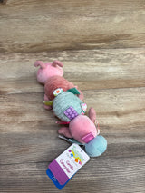 Taggies Camilla Caterpillar plush baby toy with pastel colors and sensory tags on wood background