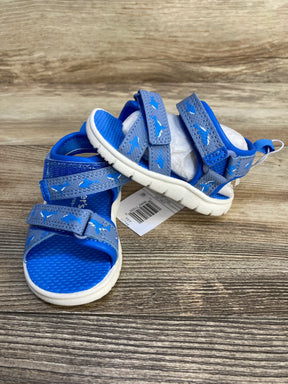 Blue toddler sandals with shark pattern and velcro straps on wood background