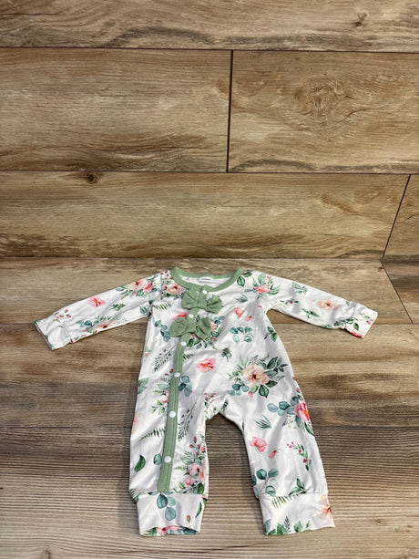 Flat lay of newborn white floral coverall with mint-green trim, two chest bows and snap-front closure on wood background
