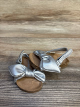 Silver toddler sandals with bows and cork soles on wooden background