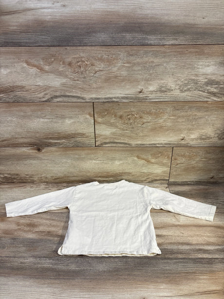 Back view of Zara ivory long sleeve toddler shirt showcasing long sleeves and raw hem on wood floor background