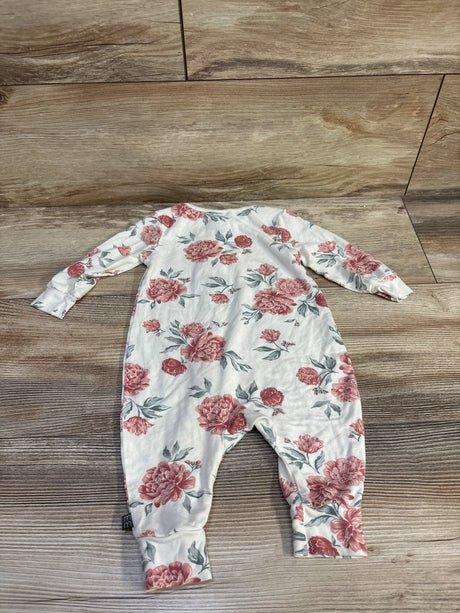 Flat lay of ivory footless baby sleeper with pink floral print and long sleeves on wood floor background