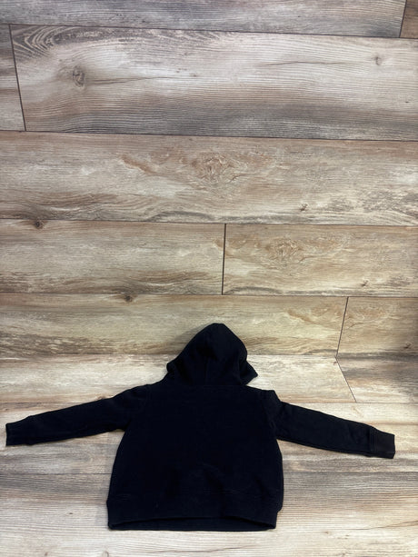 Rear view of black Nirvana pullover hoodie sweatshirt, size 3T, showing hood, long sleeves, and ribbed hem on wood floor