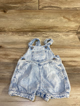 Flat lay of light blue Baby Gap denim shortalls, size 12-18 months, with bib pocket, adjustable straps and front pockets on wood background
