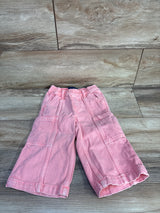 Top-down view of Baby Gap pink baggy cargo jeans with elastic waist and cargo pockets on wood background, size 18–24M