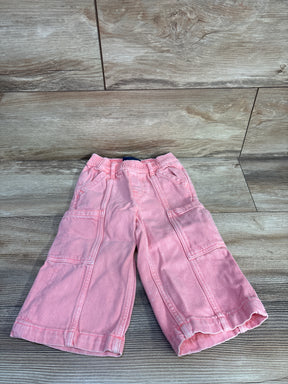 Top-down view of Baby Gap pink baggy cargo jeans with elastic waist and cargo pockets on wood background, size 18–24M