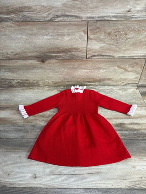 Red baby dress with white ruffles, long sleeves, smocked bodice on wood floor