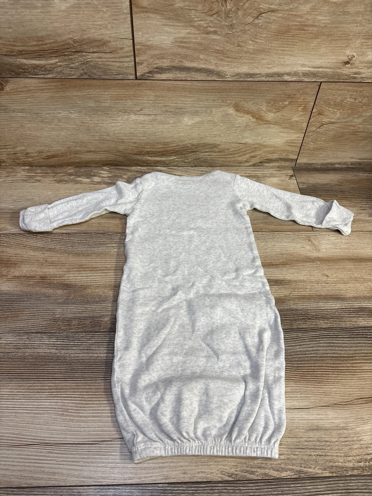 Flat lay of Simple Joys Loved gown showing long sleeves with fold over mitten cuffs and elastic bottom on wood floor