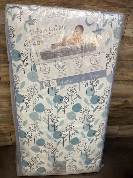 Front view of Dream On Me Inner Spring Crib & Toddler Mattress showcasing floral waterproof vinyl cover on wood floor