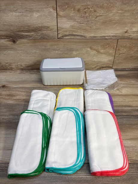 Reusable cloth diapers with colorful trim and storage container on wood floor