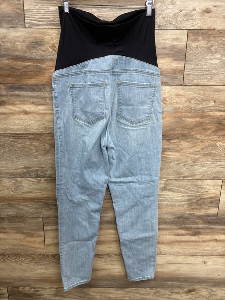 Light blue maternity jeans with black stretchy waistband hanging against wood floor background