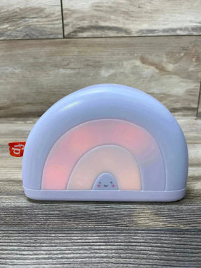 Front view of Fisher-Price Soothe & Glow Rainbow sound machine showcasing soft pink nightlight glow and smiling face on wood tabletop