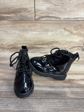 Pair of shiny black toddler boots with laces on wood-textured background