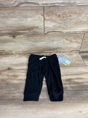 Black baby pants with white drawstring and tag, displayed on wood floor