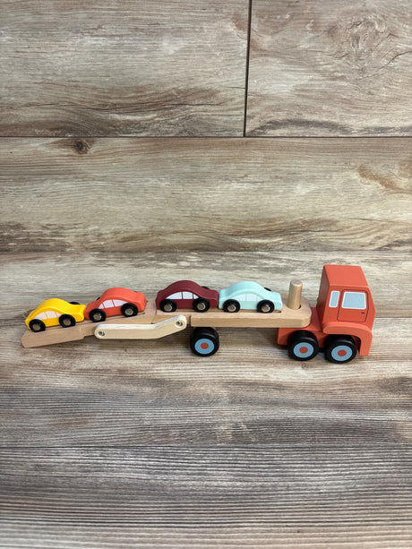 Wooden toy car carrier truck with four colorful cars on wood background