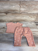 Peach baby outfit set with short sleeve top and rainbow print pants on wood background